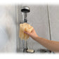 Mano sosteniendo una esponja vegetal de luffa mojada bajo el agua de la ducha de una baño.